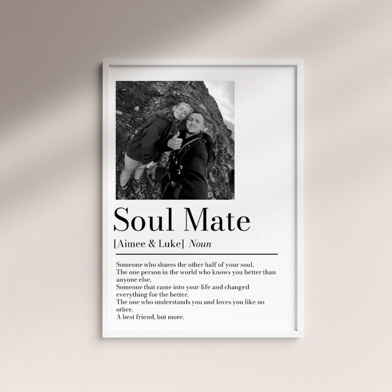 May include: A framed black and white print featuring a photograph of two people smiling. The print includes the text "Soul Mate" with a definition below, and the names "Aimee & Luke". The print is in a white frame.