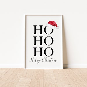Puede incluir: Un p&oacute;ster imprimible blanco con texto negro que dice "HO HO HO Feliz Navidad" con un gorro de Pap&aacute; Noel rojo encima del primer "HO".