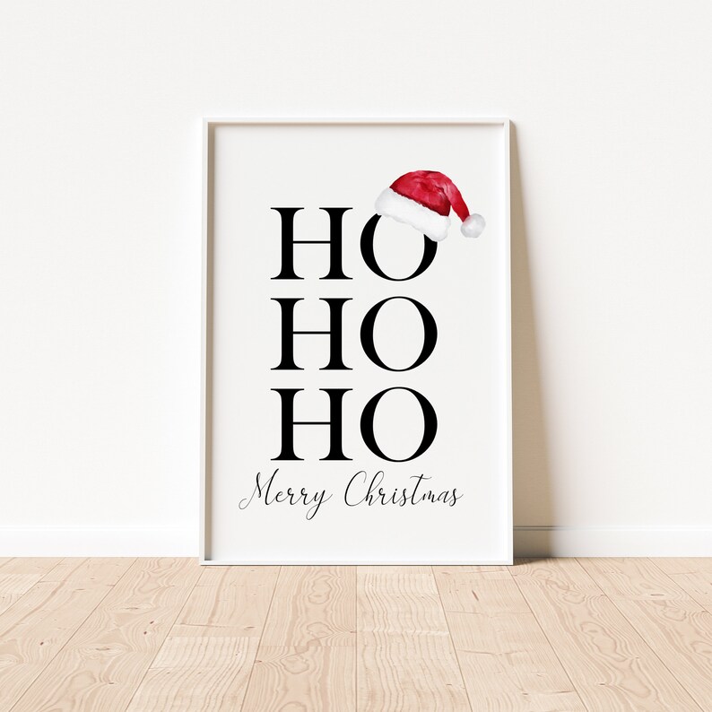 Puede incluir: Un p&oacute;ster imprimible blanco con texto negro que dice "HO HO HO Feliz Navidad" con un gorro de Pap&aacute; Noel rojo encima del primer "HO".