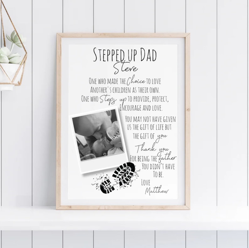 May include: Black and white printable art print with a photo of a father holding a baby. The text reads "Stepped Up Dad Steve" and includes a poem about a stepdad. The print also includes two black footprints.