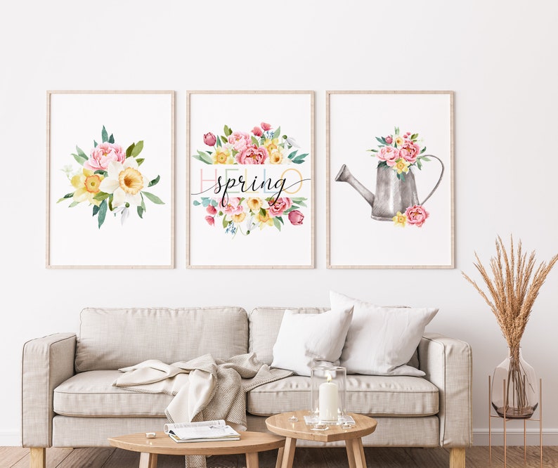 May include: Three watercolor prints featuring floral arrangements with a spring theme. The center print features the text "hello spring" in a colorful font. The left print shows a bouquet of pink and yellow flowers. The right print shows a watering can filled with flowers.
