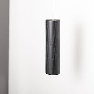 May include: A black wooden pull chain for a light fitting. The chain is hanging from the ceiling.