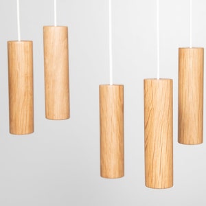 May include: Five wooden light pull chains hanging from white cords against a white background. The light pulls are cylindrical and have a natural wood grain finish.