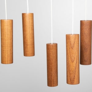 May include: Five wooden pull chains hanging from white cords against a white background. The pull chains are cylindrical and have a wood grain pattern.