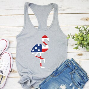 May include: A gray tank top with a flamingo silhouette design. The flamingo is filled with the colors of the American flag, red, white, and blue.