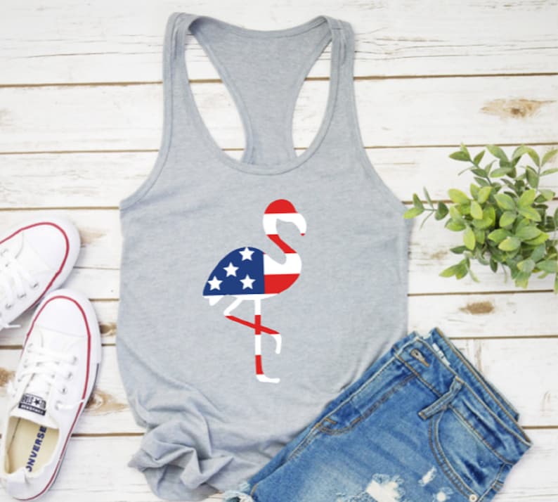 May include: A gray tank top with a flamingo silhouette design. The flamingo is filled with the colors of the American flag, red, white, and blue.