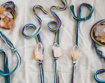 Puede incluir: Cinco collares con puntas de cristal y cordones de diferentes colores. Los cordones son de color turquesa, morado, verde, marrón y azul. Los cristales son transparentes con un tono naranja claro.