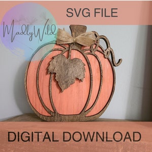 Könnte beinhalten: Eine digital herunterladbare SVG-Datei eines Kürbisses mit einem Blatt und einer Schleife. Der Kürbis ist orange und das Blatt ist braun. Die Schleife ist aus Sackleinen.