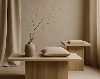 May include: A neutral-toned living space with wooden furniture. A low coffee table with a slatted base holds a vase with branches and a beige cushion. A matching side table is in the background, creating a cohesive aesthetic.