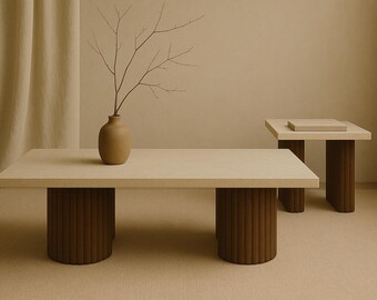 May include: A light-coloured rectangular coffee table with two cylindrical, ribbed brown legs. A smaller square side table with similar legs is in the background. A vase with branches sits on the coffee table.