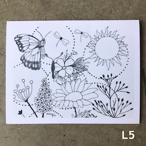 Puede incluir: Ilustración en blanco y negro de una mariposa, flores, un sol y otros elementos botánicos. La obra de arte está dibujada a mano con líneas finas y detalles, creando un diseño caprichoso e inspirado en la naturaleza. El texto "magi" está presente en la imagen, junto con la letra "L5".