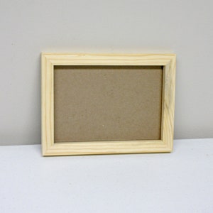 May include: A natural wood picture frame with a light brown finish. The frame is empty and ready to display a photo or artwork.