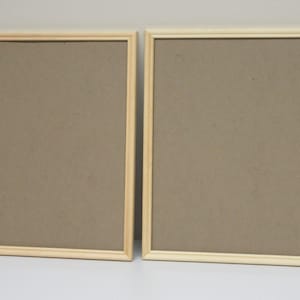 May include: Two natural wood picture frames with a light brown cardboard backing.