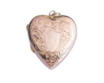 May include: A heart-shaped locket with an ornate, engraved design. The locket is gold-toned and features a shield-shaped area in the center. The surface is covered with swirling floral patterns. A small loop is at the top for a chain.