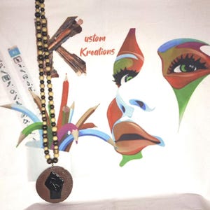 May include: A wooden beaded necklace with a round pendant featuring a black fist. The background includes a colorful artistic face and the text "ustom Kreations". Pencils and art supplies are also visible.