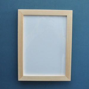 May include: A light wood picture frame with a white mat and a white background. The frame is on a blue wall.