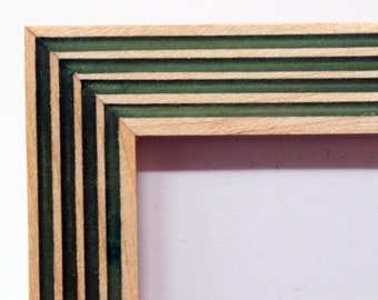 May include: A wooden picture frame with a green and natural wood layered design. The frame has a rectangular shape and a simple, clean design.