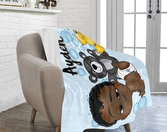 May include: A blue and white baby blanket with a cartoon illustration of a baby, a bear, and a duck. The blanket has the name "Ayden" written on it.