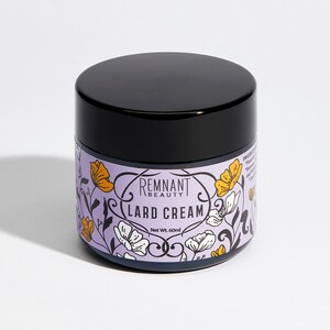 May include: A white jar with a black lid and a floral design. The jar is labeled "Remnant Beauty Lard Cream" and "Net Wt. 60 ml".