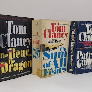 以下が含まれることがあります： トム・クランシーのペーパーバック3冊。The Bear and the Dragon、The Sum of All Fears、Patriot Games。3冊とも黒地に白文字で同じスタイルです。