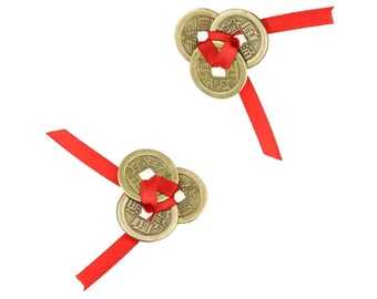 May include: Two sets of Chinese coins tied with red ribbons. Each set has three bronze-coloured coins with square holes in the centre. The ribbons are a bright red colour, and the background is white.