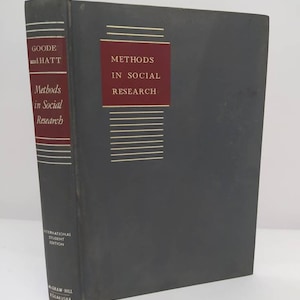 Op de afbeelding: Een donkergrijs hardback boek met de titel "Methods in Social Research" in witte tekst op een rode achtergrond. Het boek is van Goode en Hatt en is de Internationale Studenten Editie uitgegeven door McGraw-Hill Kogakusha.