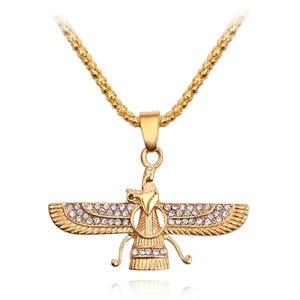 Op de afbeelding: Een goudkleurige ketting met een Faravahar-hanger. De hanger heeft de vorm van een gevleugelde figuur met een centrale cirkel en is versierd met kleine, heldere, sprankelende strass-steentjes langs de vleugels en de basis.