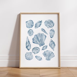 Puede incluir: Una impresi&oacute;n enmarcada con una colecci&oacute;n de conchas marinas azules en acuarela. La obra de arte muestra varias formas y tama&ntilde;os de conchas, creando un tema costero. Las conchas est&aacute;n pintadas en tonos azules sobre un fondo blanco, enmarcadas en madera clara.