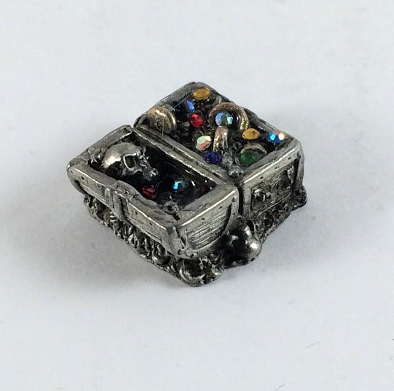 May include: A pewter treasure chest with a skull inside and a lid open to reveal colorful gems and gold coins.