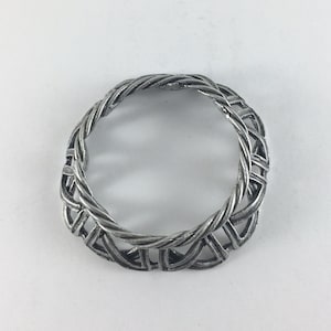 May include: A silver ring with a braided design. The ring is round and has a smooth finish.