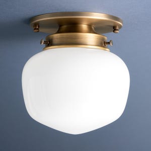 May include: A white glass globe ceiling light fixture with a brass finish. The fixture has a round base and a white globe shade.