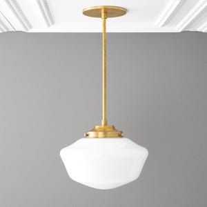 May include: A gold pendant light with a white glass shade. The light is hanging from a white ceiling.