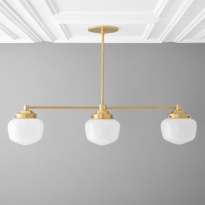 May include: A gold three-light pendant light fixture with white glass shades.