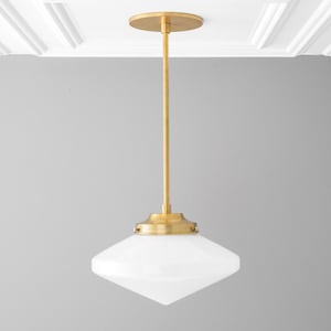 May include: A gold pendant light with a white, diamond-shaped glass shade.