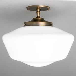May include: A white glass ceiling light fixture with a brass finish. The light has a rounded, octagonal shape.