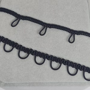 Bordure noire à passants pour robe. Garniture à deux styles avec passants élastiques pour vos vêtements ou vos travaux manuels.