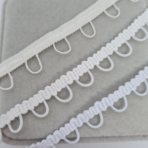 Passante elastico per bottoni bianchi dell'abito da sposa I passanti elastici per bottoni da sposa sono bianchi e bianco sporco