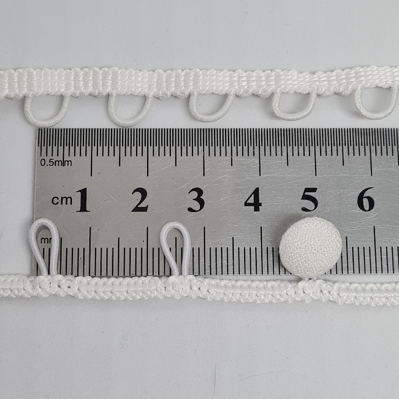 Off-white button loop trim of the bridal dress. Wedding button elastic loops.