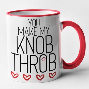 May include: White ceramic coffee mug with a red rim and handle. The mug has black text that reads "You make my knob throb" with a red angry face emoji. There are five red hearts at the bottom of the mug.