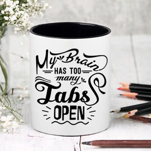 May include: White ceramic mug with a black rim and a black graphic that says "My Brain Has Too Many Tabs Open".