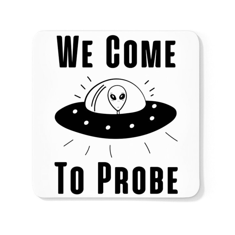 Op de afbeelding: Een witte vierkante onderzetter met zwarte tekst die "WE COME TO PROBE" luidt. Een zwart-witte cartoon UFO met een alien erin bevindt zich in het midden van de onderzetter.