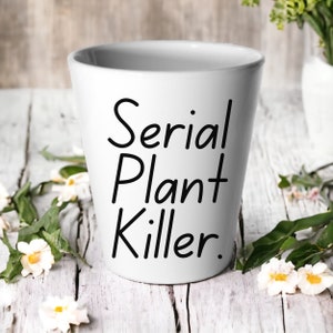 May include: White ceramic planter with black text that reads "Serial Plant Killer."