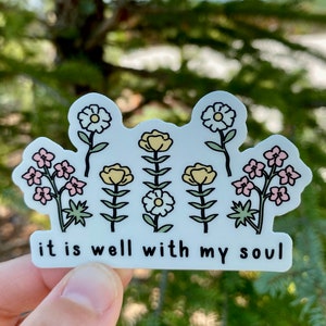 May include: White sticker with a floral design and the text "it is well with my soul". The flowers are yellow, pink, and white.