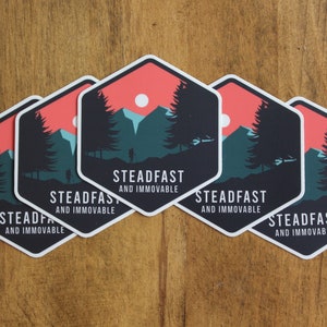 May include: Five hexagonal stickers with a mountain scene and the text "STEADFAST AND IMMOVABLE". The stickers are printed on white paper with a red, blue, and green color scheme.