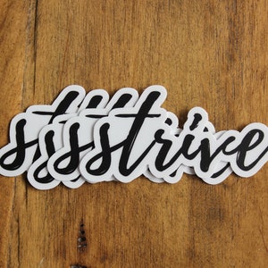 May include: Multiple white stickers with the word "STRIVE" written in black cursive lettering.