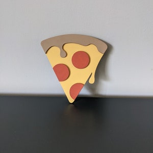May include: A brown, yellow, and red pizza slice with three pepperoni slices and a brown drip of sauce.