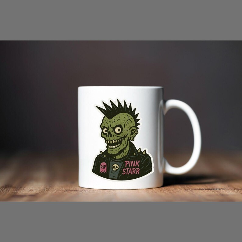May include: White ceramic mug featuring a green zombie with a black leather jacket and a mohawk. The mug has the text "PINK STARR" and a skull graphic. The mug is on a wooden surface.