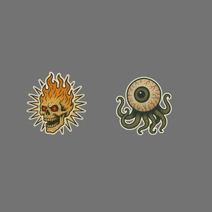 May include: Two sticker designs on a gray background. One features a skull engulfed in flames with red eyes and a yellow outline. The other is an eyeball with tentacles, in shades of green and brown, with a yellow outline.