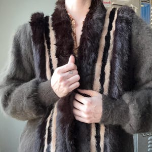 May include: A vintage coat in shades of brown, black, and beige. The coat has vertical stripes and a plush, textured appearance. The collar and front panels have a darker, fur-like trim, adding a touch of luxury to the garment.
