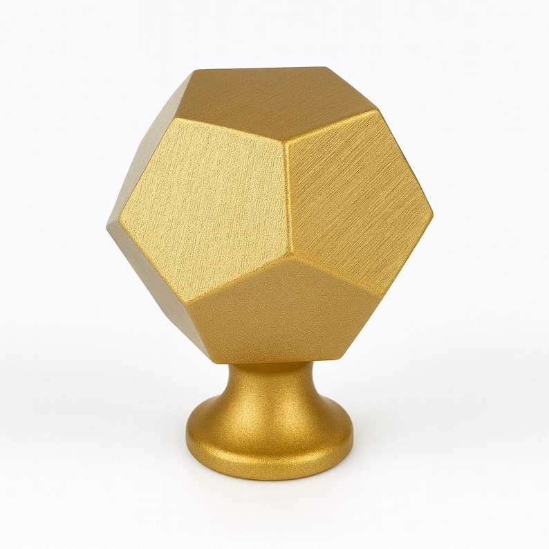 K&ouml;nnte beinhalten: Goldfarbener Schrankknopf mit geometrischem, facettenreichem Design. Der Knopf hat einen Sockel und ein geb&uuml;rstetes Metall-Finish. Diese dekorative Hardware ist f&uuml;r Schubladen und Schr&auml;nke geeignet.